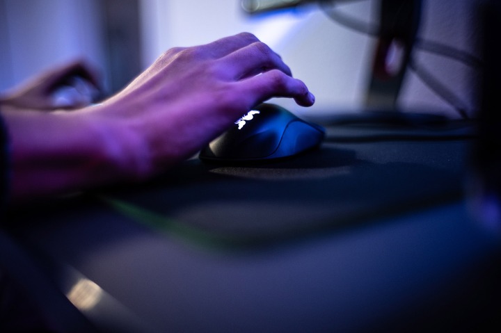 Main sur une souris d'ordinateur, éclairage violet.